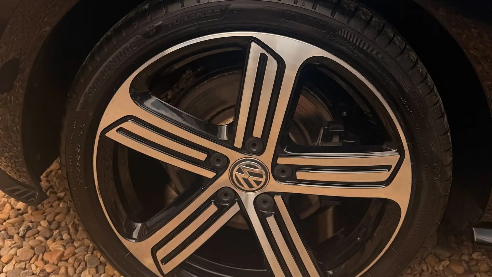 Close-up of a cleaned alloy wheel and glossy dark paintwork