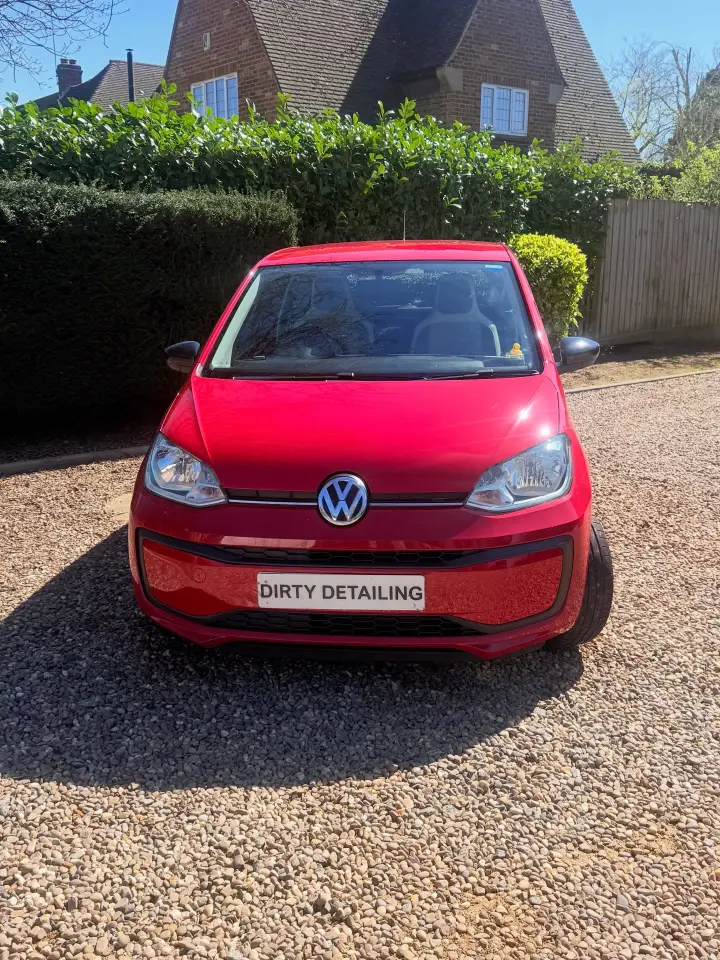 Red Volkswagen up! after mobile detailing on a gravel driveway